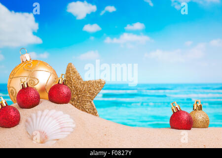 Weihnachtsschmuck und Kugeln in den Sand am Strand auf einem hellen, sonnigen Tag. Stockfoto