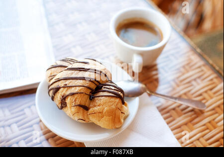 Tasse Kaffee und ein Croissant auf dem Tisch Stockfoto