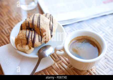 Tasse Kaffee und ein Croissant auf dem Tisch Stockfoto
