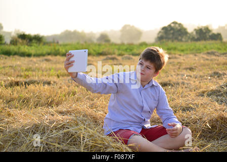 Junge Teenager spielen auf einem Tablet im Feld Stockfoto