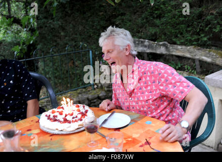 Mann in seinen 50er Jahre feiert seinen Geburtstag Ausblasen der Kerzen auf der Torte Stockfoto