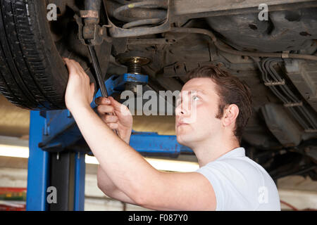 Mechaniker arbeiten am Rad unter Wagen Stockfoto