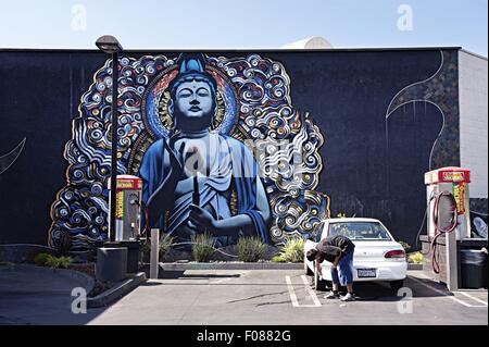 Mann Waschen Auto gegen die Wand Graffiti von Buddha, Los Angeles, Kalifornien, USA Stockfoto