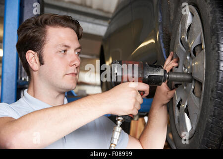 Mechaniker In Garage mit Druckluft-Hammer auf Auto-Rad Stockfoto