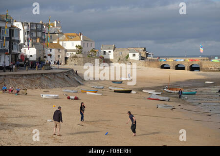 St. Ives, Cornwall, UK: Drei Familienmitglieder spielen Frisbee am Strand in der späten Nachmittagssonne Stockfoto