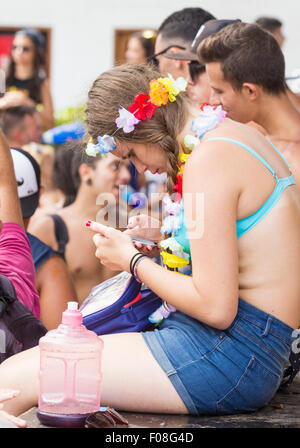 Junge Frau mit Handy beim Festival, blind auf die laute Musik und Menschenmassen. Stockfoto