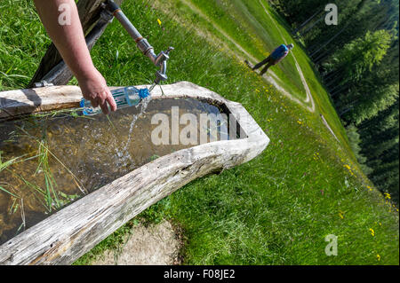 Plastikflasche mit Wasser aus einem Wasserhahn füllen gespeist aus einem Gebirgsbach in den österreichischen Bergen. Stockfoto