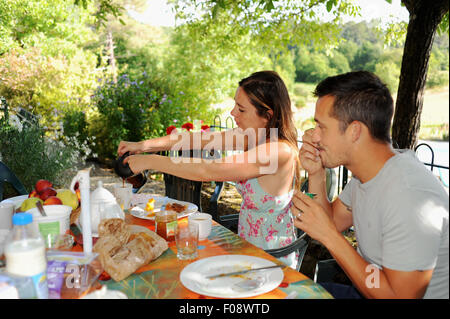 Junges Paar Essen und frisches zubereitetes Frühstück im Freien auf Sommertag auf ihren Urlaub-Ferienhaus in der Region von Frankreich viel Auswahl Stockfoto