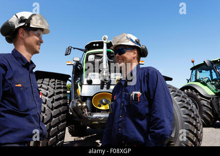 zwei Mechaniker mit riesigen landwirtschaftlichen Traktoren Stockfoto