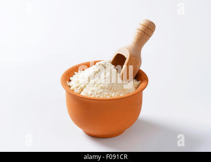 Fein gemahlenes Mehl und hölzerne Schaufel in Terrakotta-Schale Stockfoto