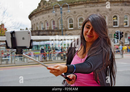 Junge Frau mit Selfie-Stick mit dem Apple iPhone und Leeds Corn Exchange im Hintergrund Stockfoto