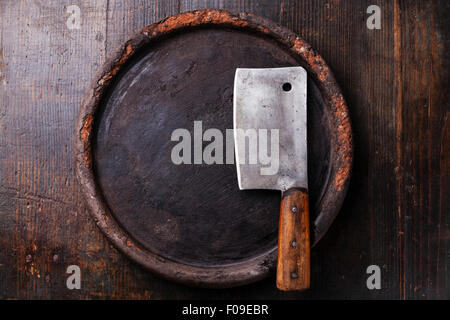 Runde Steinoberfläche und Fleischerbeil auf dunklem Holz Stockfoto