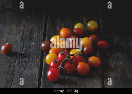 Sortiment von Cherry-Tomaten rot, gelb und Orange über alten Holztisch. Dunkel rustikalen Stil. Tageslicht. Stockfoto