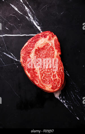 Rohe marmorierte Frischfleisch Black Angus Steak Ribeye auf schwarzem Marmor Hintergrund Stockfoto