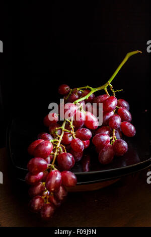 Frische rote Trauben in einem Haufen auf einem dunklen Hintergrund Stockfoto