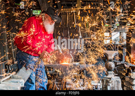 Schmied Pfund Metall mit Hammer während der Demonstration am Silver Dollar City, 1880er Jahre Thema Vergnügungspark in der Nähe von Branson, Missouri. Stockfoto