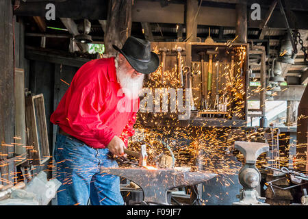 Schmied Pfund Metall mit Hammer während der Demonstration am Silver Dollar City, 1880er Jahre Thema Vergnügungspark in der Nähe von Branson, Missouri. Stockfoto