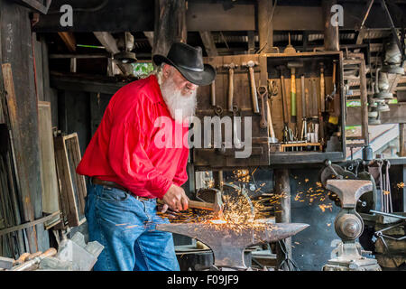 Schmied Pfund Metall mit Hammer während der Demonstration am Silver Dollar City, 1880er Jahre Thema Vergnügungspark in der Nähe von Branson, Missouri. Stockfoto