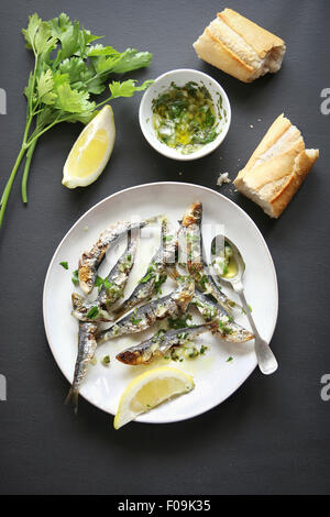 Gegrillte Sardinen mit Salsa Verde auf einem Teller. Ansicht von oben Stockfoto