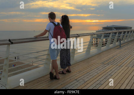 Paar genießt die Aussicht auf den Sonnenuntergang vom Scheveningen Pier auf dem Oberdeck, den Haag (Den Haag), Süd-Holland, Niederlande. Stockfoto