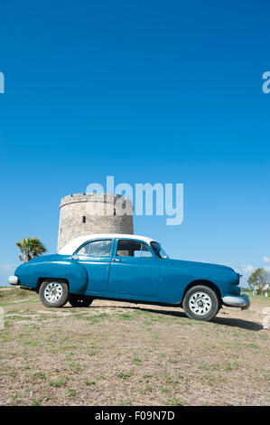 VARADERO, Kuba - 7. Juni 2011: Klassische amerikanische Oldtimer parkte vor einem Stein Wachturm erbaut in den 1930er Jahren. Stockfoto