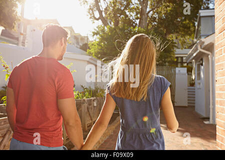 Rückansicht der jungen Paare, die in ihrem Haus zusammen. Paar im Hinterhof nehmen Fuß an einem sonnigen Tag. Stockfoto