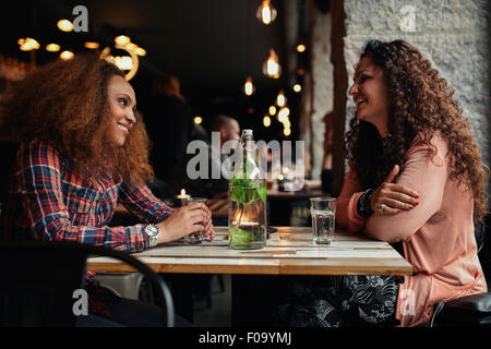 Bild von Freundinnen treffen in einem Café. Zwei junge Frauen in einem Restaurant sprechen und Lächeln. Stockfoto