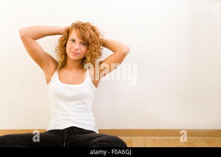 Junge rothaarige Frau stützte sich auf indoor-Wand Stockfoto