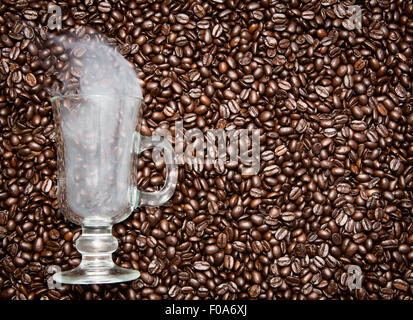 Irish Coffee Glas stecken in frischen Kaffeebohnen. Rauch kommt aus dem Glas. Stockfoto