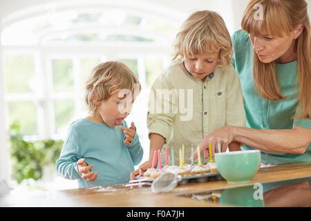 Mutter und Söhne machen Cupcakes in Küche Stockfoto