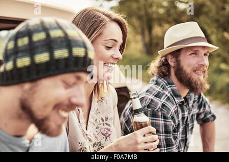 Drei Leute halten Flaschenbier lächelnd Stockfoto