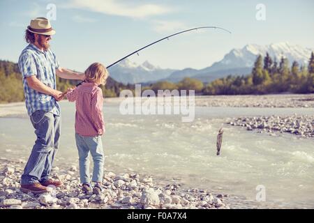 Mitte erwachsenen Mann und der junge Fluss halten Angelrute mit Fisch befestigt, Wallgau, Bayern, Deutschland Stockfoto