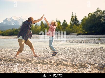 Seitenansicht des jungen Mannes und jungen springen, dabei hohe fünf, Wallgau, Bayern, Deutschland Stockfoto