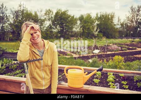 Reife Frau, Gartenarbeit, stützte sich auf Rechen, lachen Stockfoto