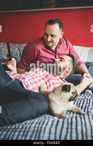 Gay paar mit Hund, mit Smartphone im Schlafzimmer Stockfoto