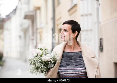 Frau mit Blumen auf Straße Stockfoto