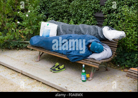 PARIS, Frankreich - 27. Juli 2015: Ein Obdachloser auf einer Bank in einem Park in Paris in Frankreich schläft Stockfoto