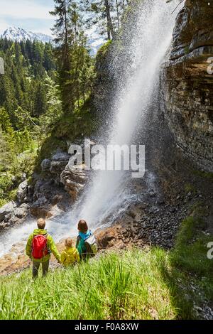 Junge Familie im Wald, stehend, beobachtete Wasserfall, Rückansicht Stockfoto