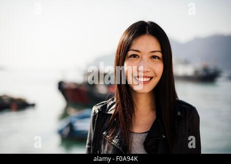 Porträt der jungen Frau vor Boote auf dem Wasser, Blick auf die Kamera zu Lächeln Stockfoto