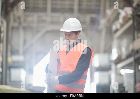 Junge männliche Lagerarbeiter Prüfung Plank im Lager Stockfoto