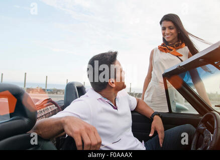 Mann im Cabrio, Frau neben dem Auto stand lächelnd Stockfoto