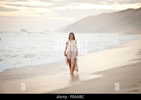 Mitte der erwachsenen Frau am Strand entlang zu laufen Stockfoto