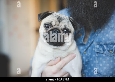 Young bärtiger Mann mit Hund auf Arm Stockfoto