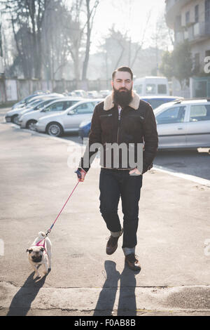 Junge bärtige Mann gehen Hund auf der Straße Stockfoto