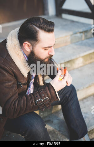 Junge bärtige Mann Pfeife auf Treppe Stockfoto