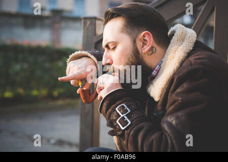 Junge bärtige Mann Pfeife auf Treppe Stockfoto