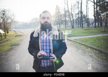 Young bärtiger Mann mit digital-Tablette im park Stockfoto