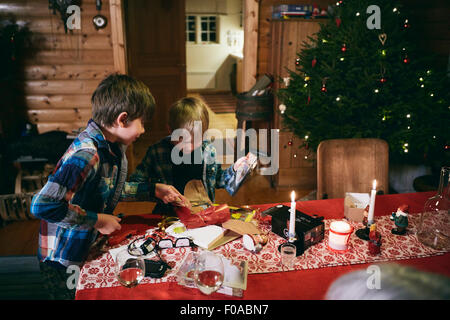 Zwei Brüder, die Weihnachtsgeschenke am Tisch öffnen Stockfoto