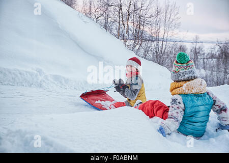 Zwei Brüder auf Schlitten im Schnee bedeckt Hügel, Hemavan, Schweden Stockfoto