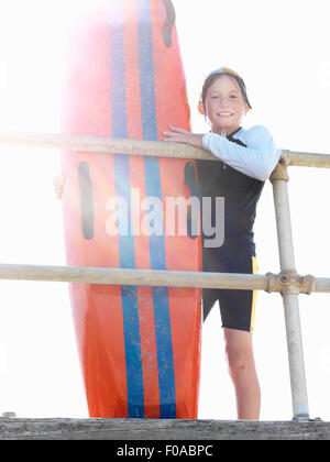 Porträt des jungen Nipper (Kind Surf Life Savers) gelehnt Geländer in Sonnenlicht, Altona, Melbourne, Australien Stockfoto